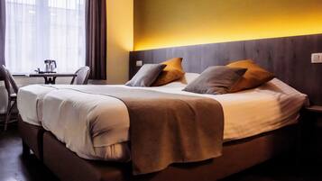 A hotel room with a bed, bedside table, and a small desk with a chair.