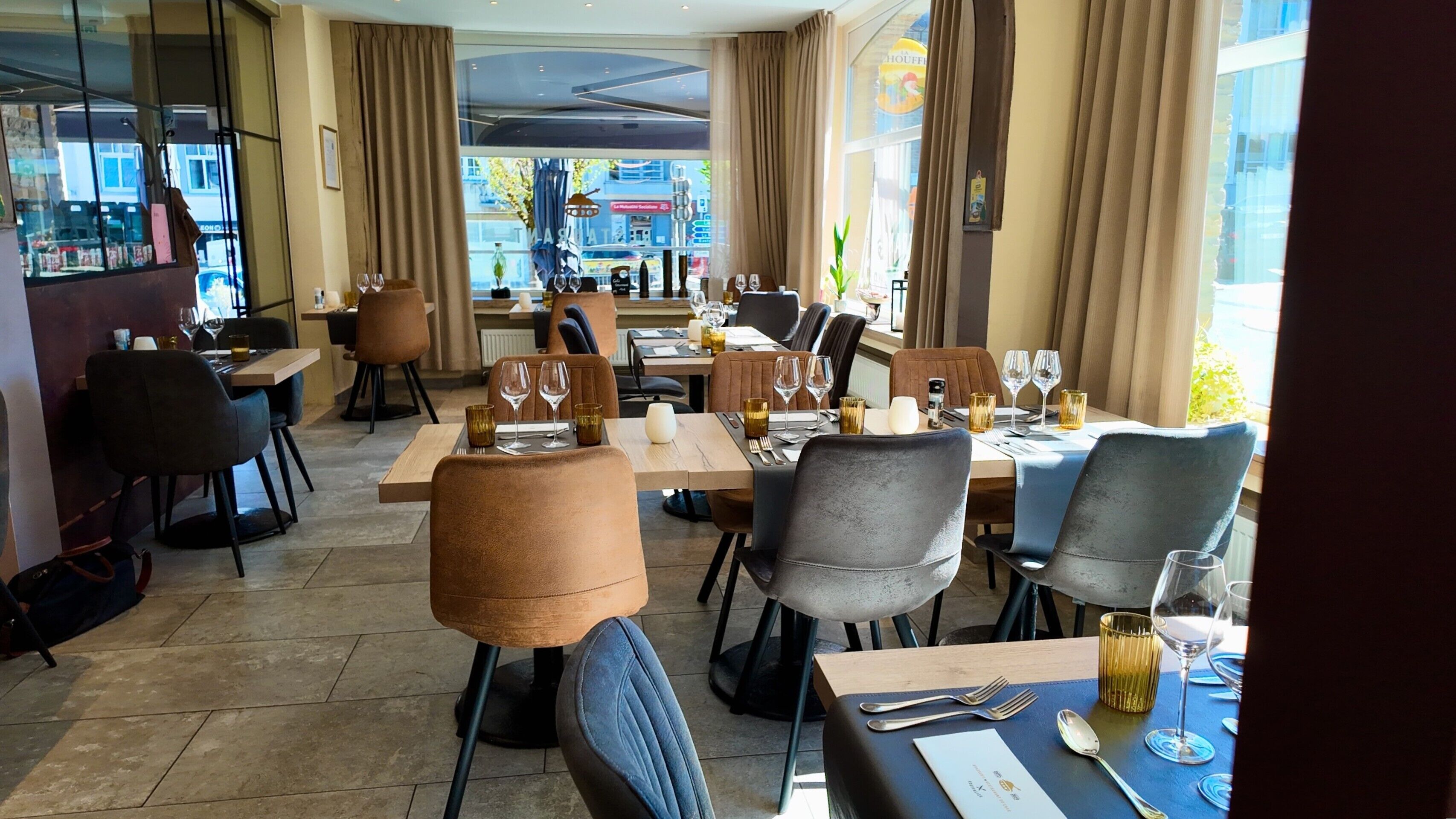 A restaurant with tables set for dining, chairs, and wine glasses.