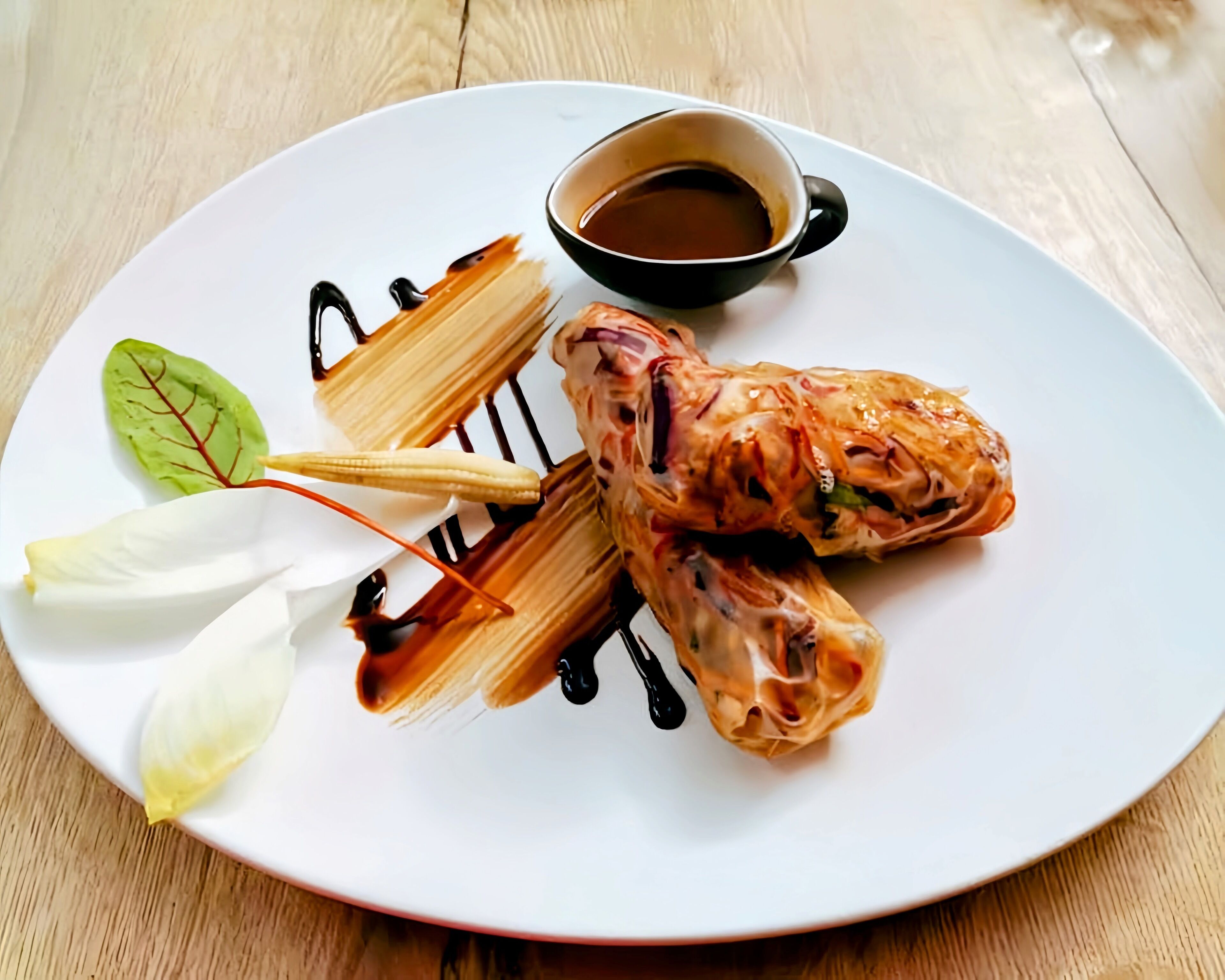 A plate with a dessert, possibly a pastry, and a small cup of sauce.