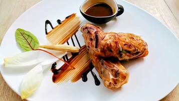 A plate with a dessert, possibly a pastry, and a small cup of sauce.