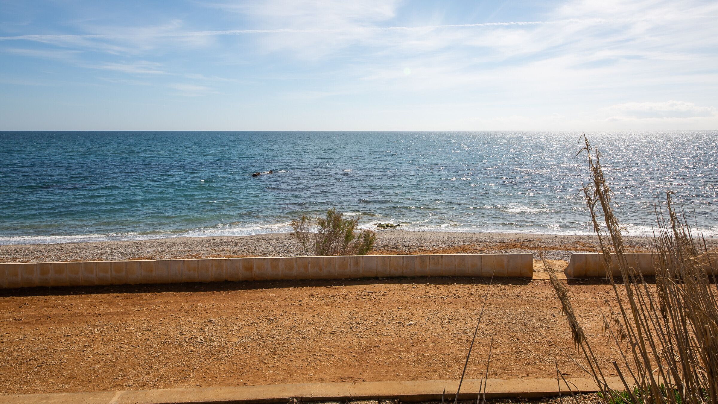 A beach with a sandy shore and a clear view of the sea.