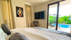 A hotel room with a large bed, a flat-screen TV, and a view of a swimming pool. - Lxry Apartment Jan Sofat With Private Pool (Willemstad)