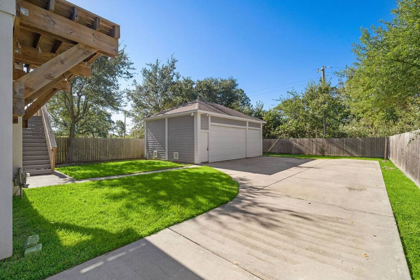 A residential backyard with a garage, a wooden deck, and a well-maintained lawn.