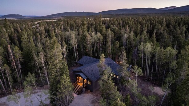 Une cabane entourée d’une forêt dense, offrant une vue dégagée sur les montagnes environnantes.