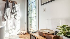 Une pièce avec une grande fenêtre, un lecteur de musique en bois, une plante et une boîte étiquetée « SMYRES HERSHEYS ».