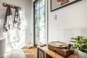 A room with a large window, a wooden music player, a plant, and a box labeled 'SMYRES HERSHEYS'. - Dog-friendly Cabin+Hot Tub+35min to Breckenridge (Fairplay)