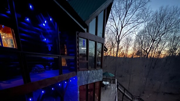A modern house with a balcony, a stone wall, and a staircase leading to the upper level.