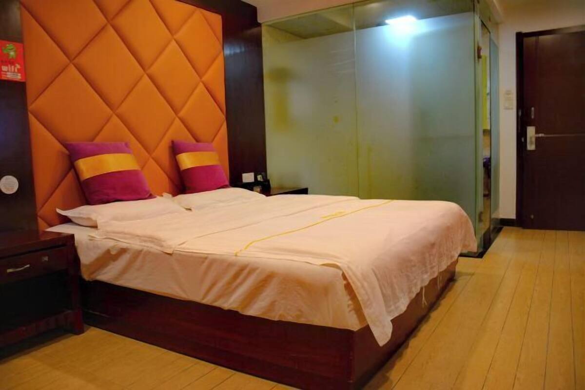 A bedroom with a bed, a nightstand, a wardrobe, and a mirror.