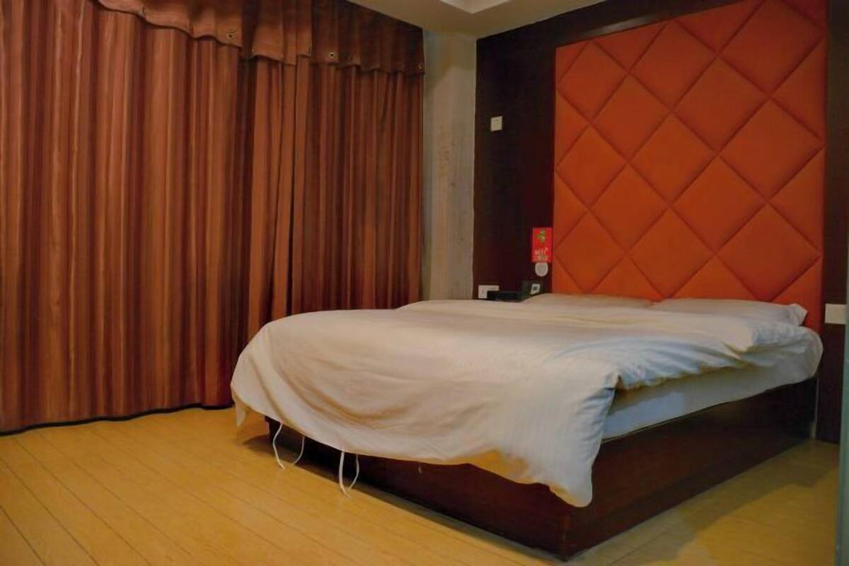 A room with a bed, curtains, and a red headboard.