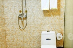 Une salle de bain équipée d’une douche, de toilettes et d’un porte-serviettes.