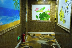 Un pasillo con un cuadro de una escena de playa, una obra de arte enmarcada con flores y un suelo con diseño.
