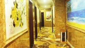A hallway with a patterned floor, framed artwork on the walls, and a door at the end.