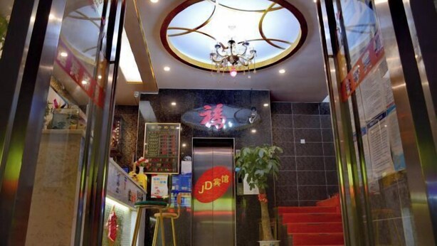 A hotel lobby with a reception desk, a chandelier, a staircase, and a large sign with Chinese characters.