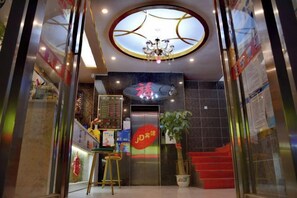 Ein Hotel mit Eingangsbereich, einer Rezeption, einer Treppe und einer Chandelier.