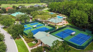 Complejo de canchas de tenis con varias canchas, piscina y zonas verdes circundantes.