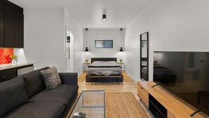Ein modernes Schlafzimmer mit Bett, Nachttischen, Fernseher und einer Couch.