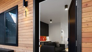 Ein modernes Interieur mit Holzfassade, eine schwarze Tür führt in einen Wohnbereich mit Sofa und Couchtisch.