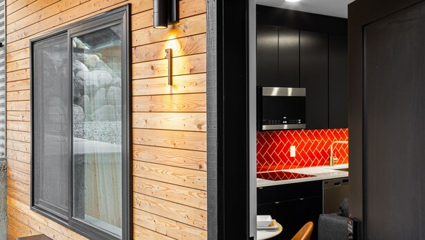Eine moderne Küche mit Holzvertäfelung, einem großen Fenster und einer roten Spritzschutzwand.