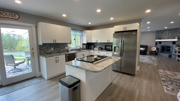 A modern kitchen with white cabinets, a stainless steel refrigerator, and a granite countertop.