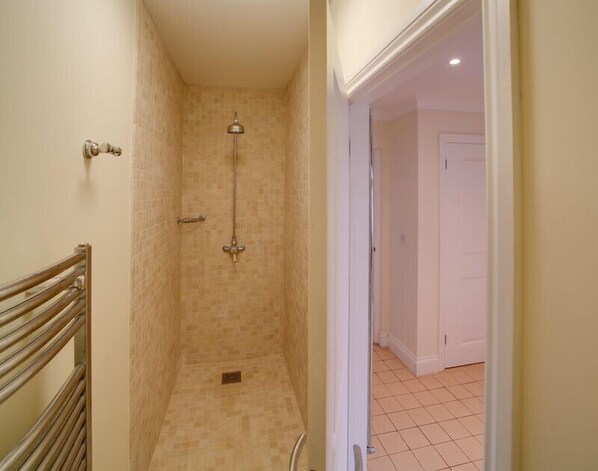 A narrow shower area with tiled walls and a metal showerhead.