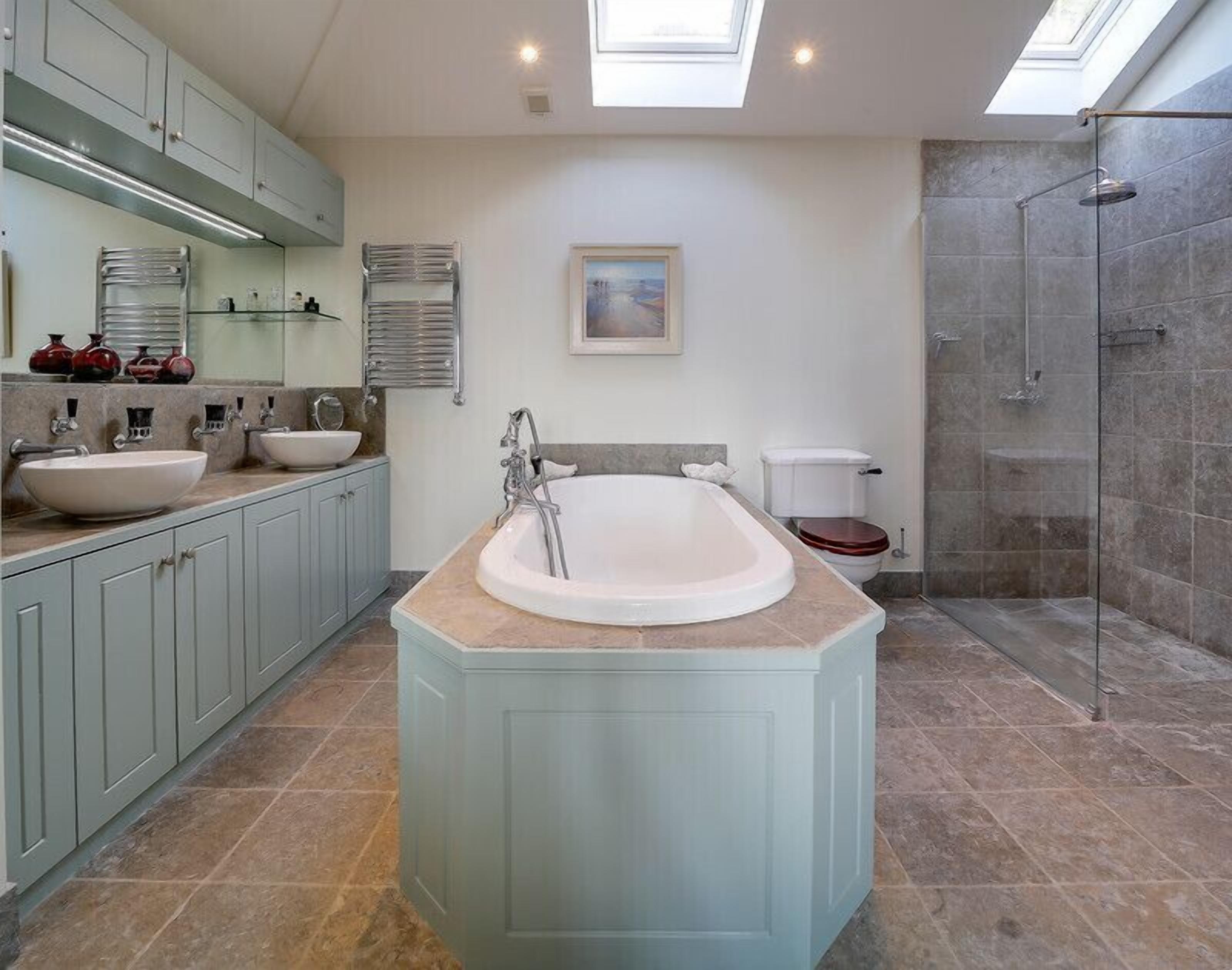 Une salle de bain moderne avec une baignoire sur pieds, deux lavabos, des toilettes et une douche à parois de verre.