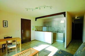 A compact living space with a dining area, a kitchenette, and a small kitchen.