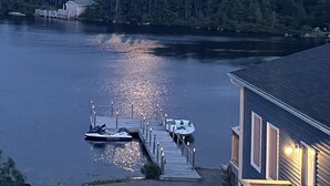 A waterfront property with a dock, boats, and a house with a visible deck.