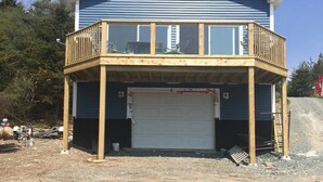 A two-story house with a wooden deck and a garage.