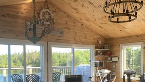 A cozy room with a pool table, wooden ceiling, and large windows overlooking a lake.