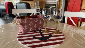 A table with a striped tablecloth, two wine glasses, and a woven bag.