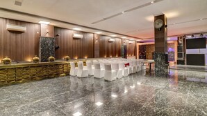 A conference room with a marble floor, white chairs, a reception desk, and wooden paneling on the walls. - Xenious Grand Manor, Golf Course Extension Road, Gurugram (Gurugram)