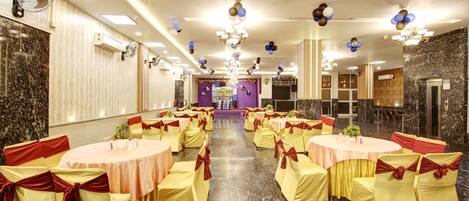Un salón de banquetes con mesas redondas, sillas, candelabros y globos.