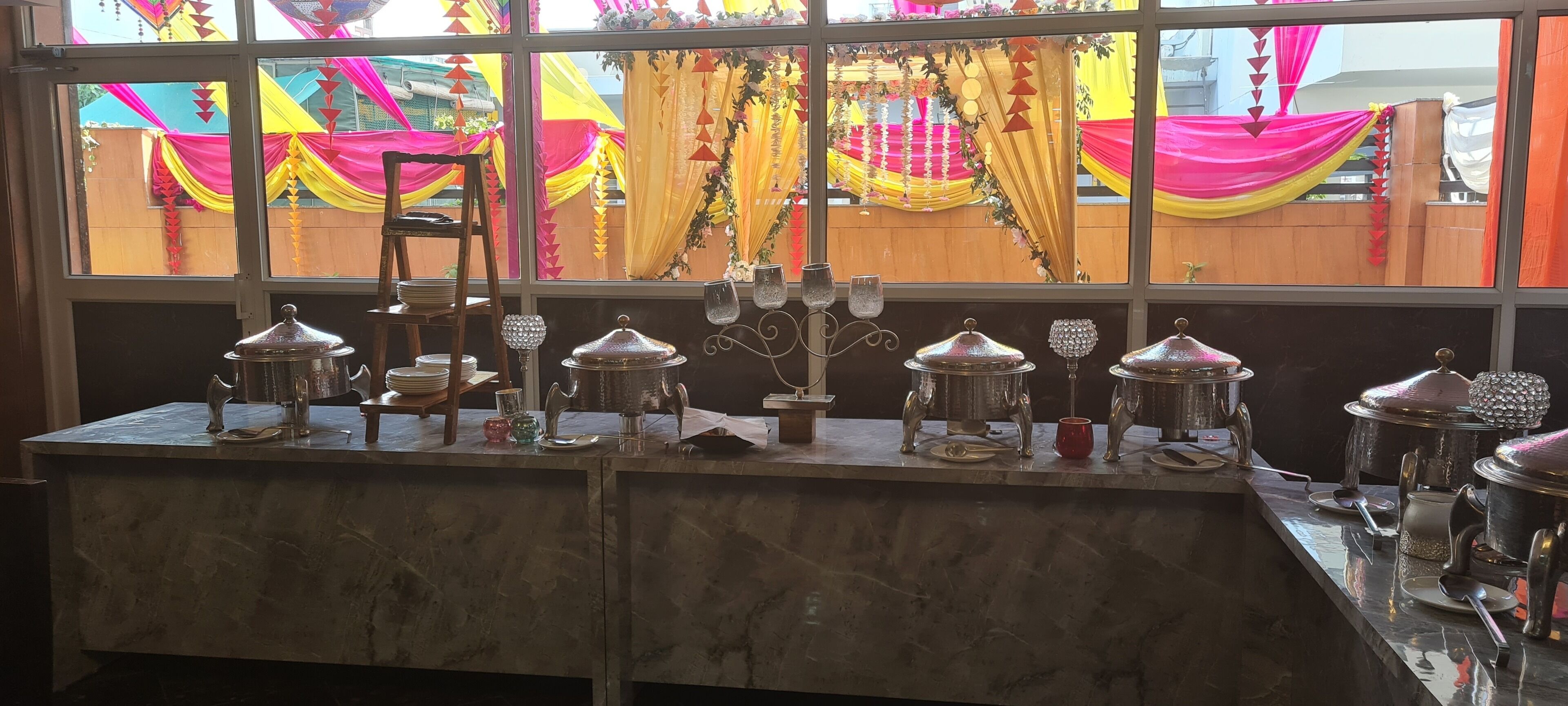 A marble counter with multiple silver pots and glassware.