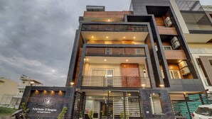A modern hotel with a glass facade, multiple balconies, and a sign indicating it is located at P-218 Sector 51 Gurugram. - Xenious Grand Manor, Golf Course Extension Road, Gurugram (Gurugram)