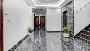 A modern hotel hallway with marble flooring, a ceiling fan, and a staircase. - Xenious Grand Manor, Golf Course Extension Road, Gurugram (Gurugram)