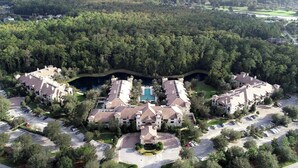 A large resort with multiple buildings, a central pool, and a surrounding forested area. - Top floor King Suite- Kitchenette- comm pool & hot tub- luxury vinyl floors (St. Augustine)