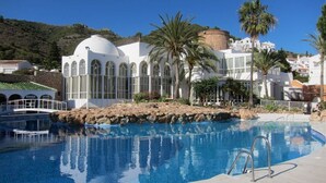 Ein Schwimmbecken mit klarem, blauem Wasser, umgeben von einem weißen Gebäude mit Bogenfenstern und einer Kuppel.