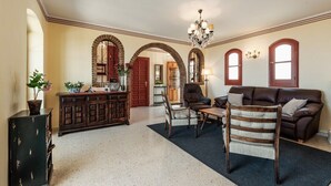 Un salón amplio con un aparador de madera oscura, un sofá de cuero marrón y una silla de madera.