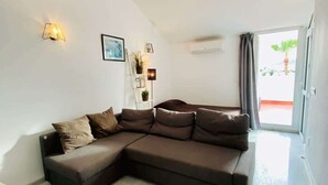 Un soggiorno moderno con un divano componibile, una lampada da terra e un quadro appeso al muro.