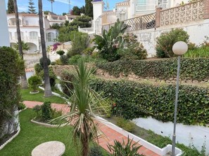 A landscaped garden with a pathway, palm trees, and a white fence. - SHR016 Apartment with a Pool in Las Rosas de Capistrano (Nerja)