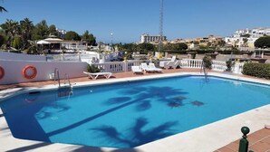 Piscina con lettini, un galleggiante e vista su una cittadina costiera.