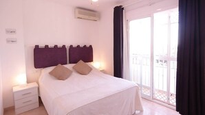 Une chambre à coucher avec un lit, une table de chevet, un ventilateur de plafond et une vue sur l’extérieur.