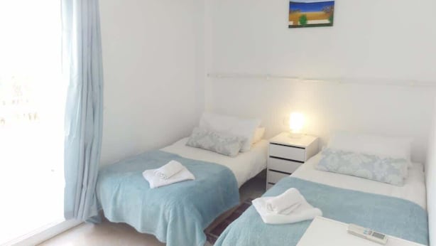 A hotel room with two beds, a bedside table, a nightstand, and a window with curtains. - SHR010 Spacious apartment with pool near the beach (Nerja)