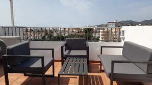 A rooftop terrace with outdoor furniture, a view of the cityscape, and a white building in the background. - SHR010 Spacious apartment with pool near the beach (Nerja)