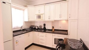 A kitchen with white cabinets, a black countertop, a microwave, a coffee maker, and a toaster. - SHR010 Spacious apartment with pool near the beach (Nerja)