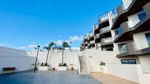 Un edificio moderno con varios balcones, una escalera y plantas en macetas.
