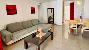 A modern living room with a sofa, a coffee table, and a dining area with chairs and a table.