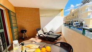A glass table with a bottle of Moët & Chandon champagne, a glass of wine, and a bowl of oranges on a balcony overlooking a cityscape.
