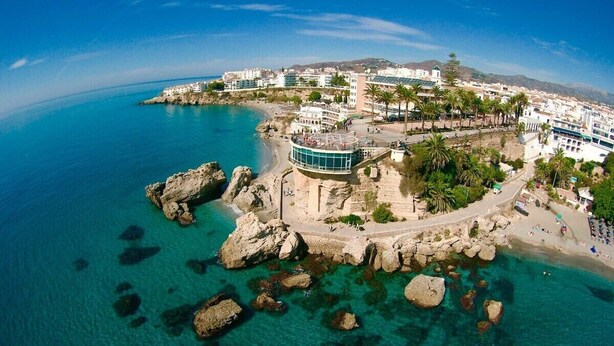 A coastal town with a prominent building featuring a curved balcony overlooking the sea.