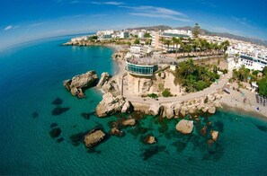 Una cittadina costiera con un edificio importante caratterizzato da un balcone curvo affacciato sul mare.